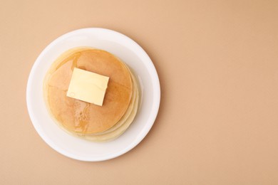 Delicious pancakes with butter and honey on beige background, top view. Space for text