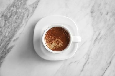 Cup of aromatic hot coffee on marble background, top view
