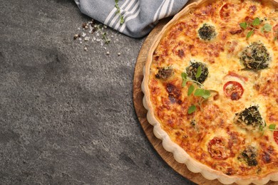 Delicious homemade vegetable quiche on gray table, top view. Space for text