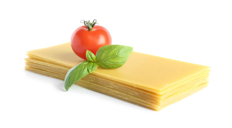 Photo of Uncooked lasagna sheets, tomato and basil on white background
