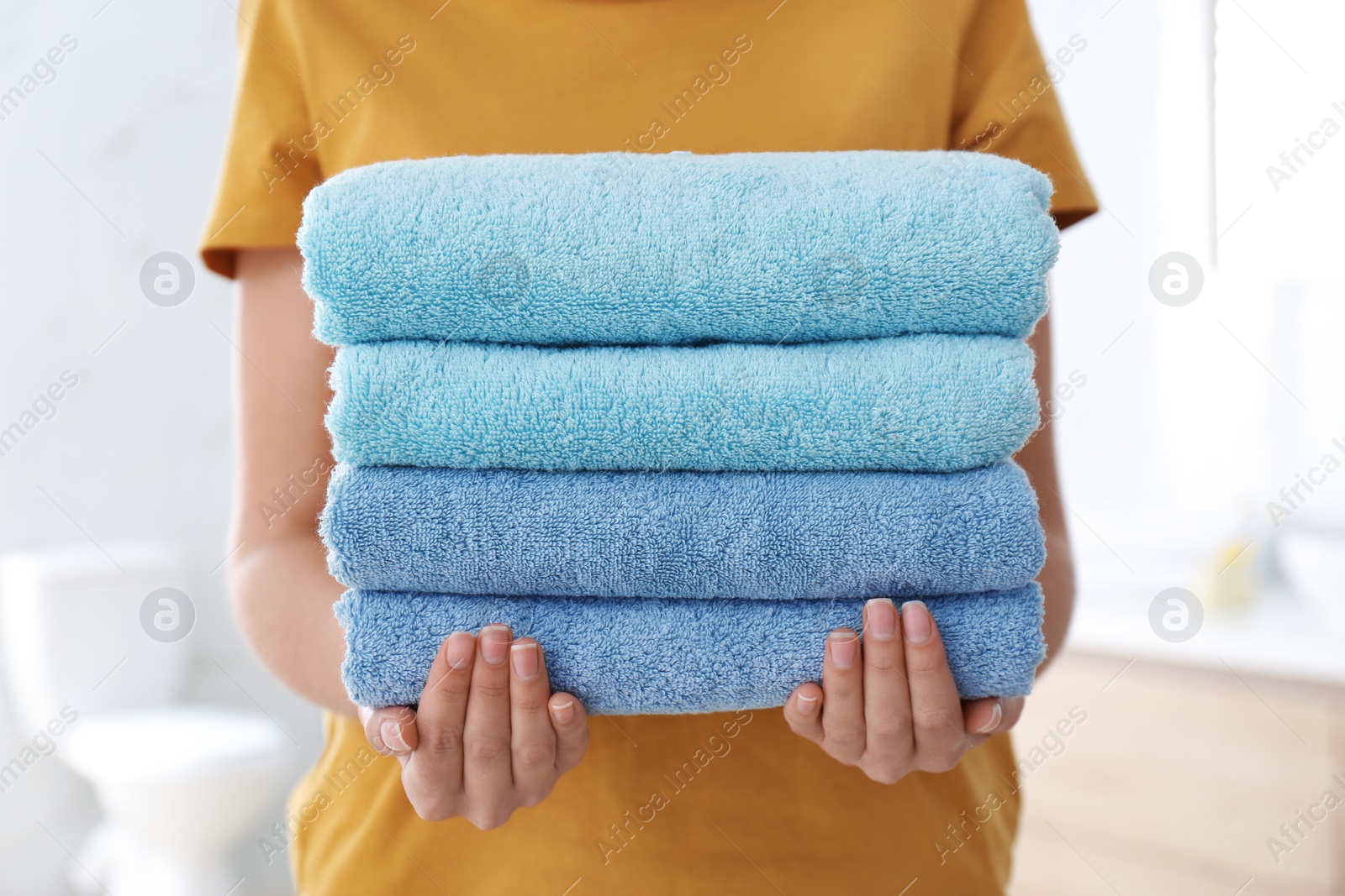 Photo of Woman holding fresh towels in bathroom, closeup