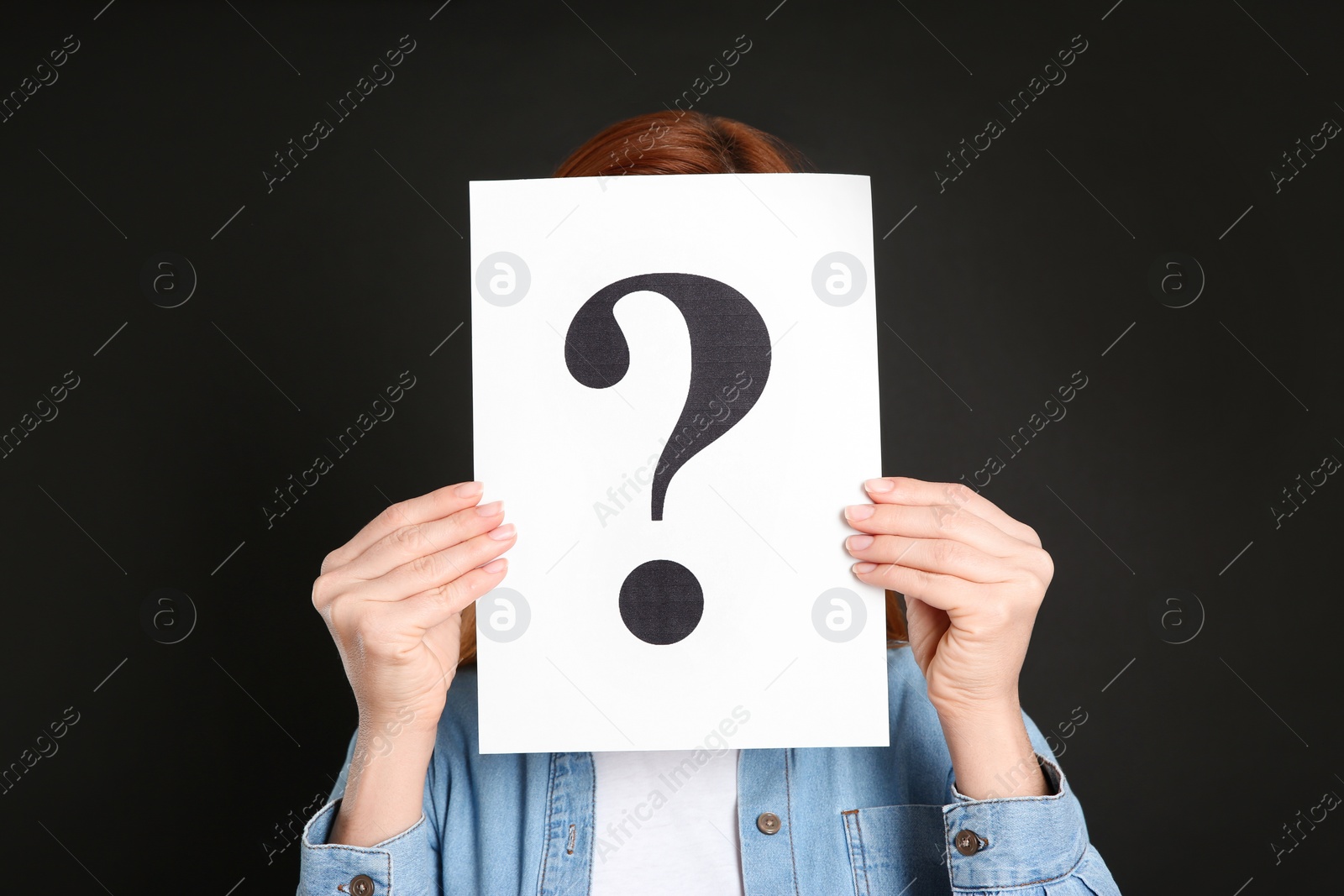 Photo of Woman holding question mark sign on black background