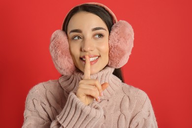 Photo of Beautiful young woman wearing earmuffs on red background