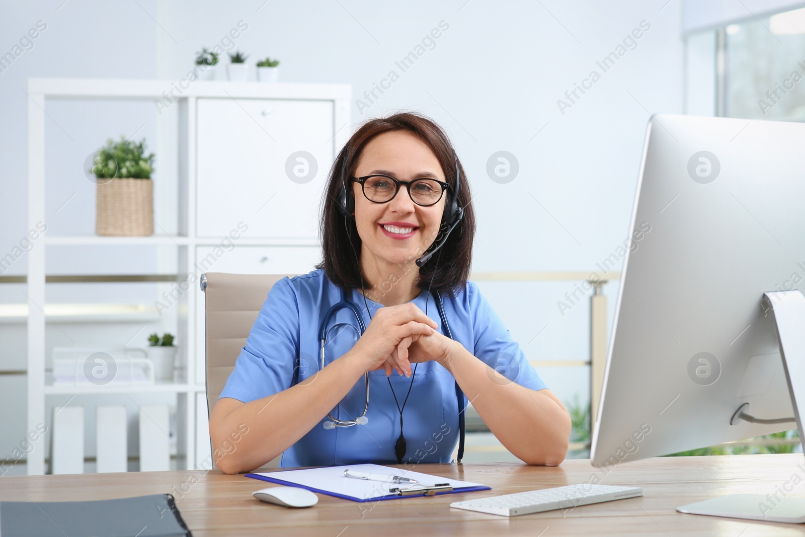 Photo of Doctor with headset at table in office. Hotline service