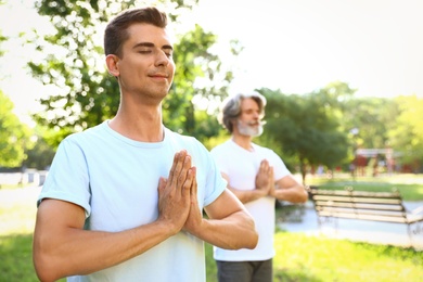 Photo of Men practicing morning yoga in sunny park