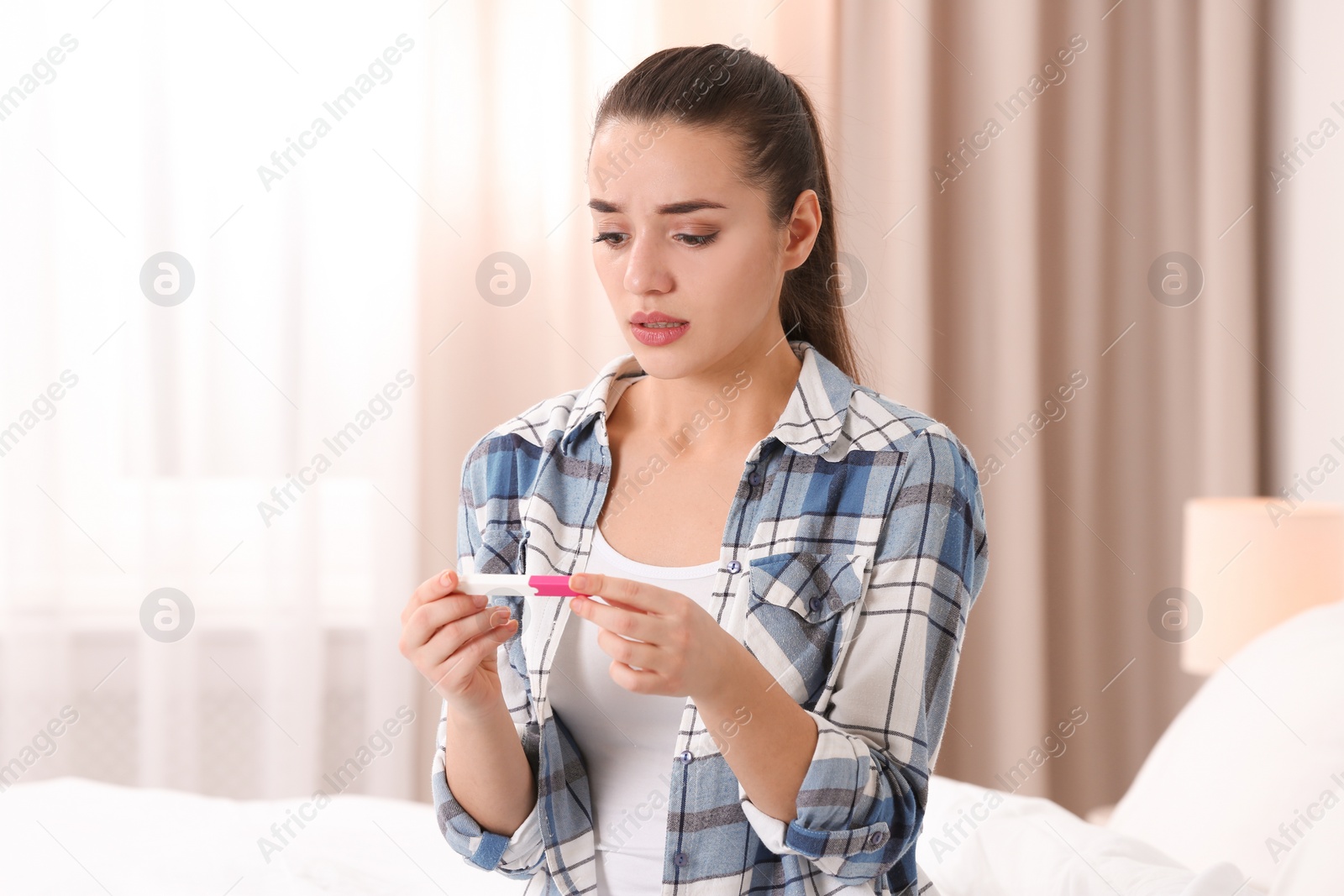 Photo of Young woman with pregnancy test at home. Gynecology and childbirth