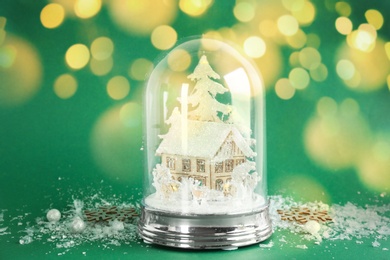 Image of Beautiful Christmas snow globe on green background, bokeh effect