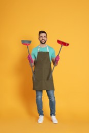 Man with broom and dustpan on orange background