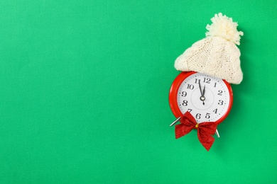 Photo of Alarm clock in hat on green background, top view with space for text. New Year countdown