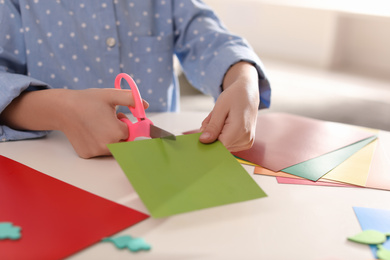 Little girl making greeting card at table indoors, closeup. Creative hobby