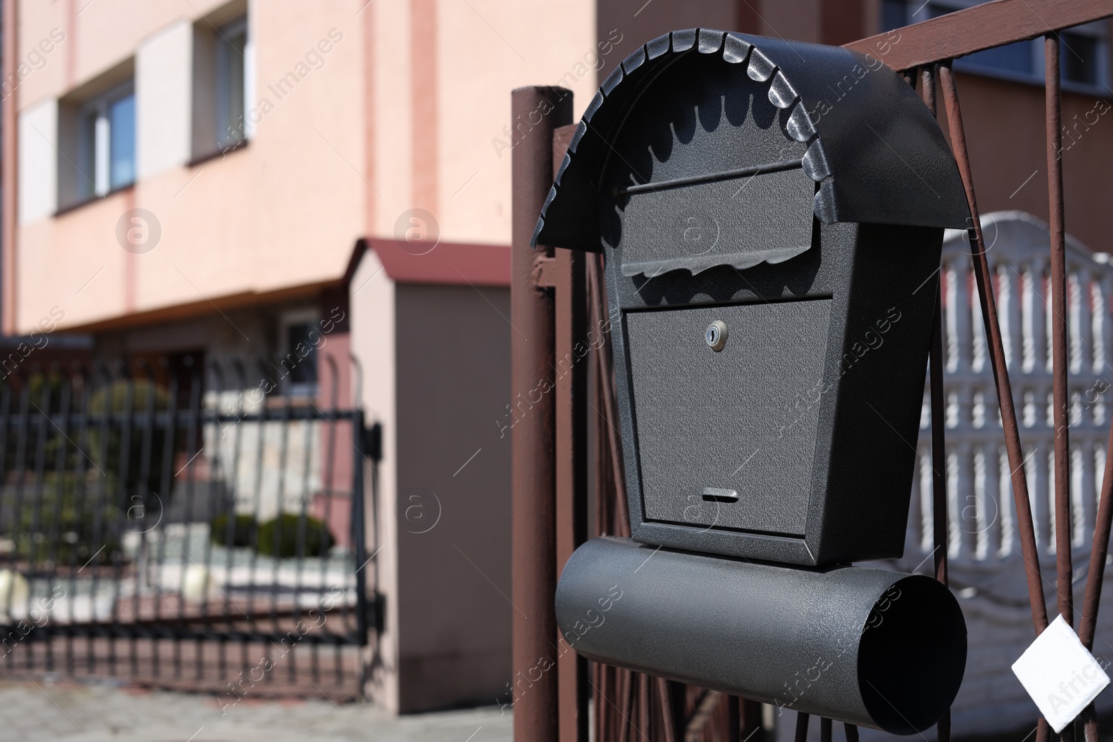 Photo of Beautiful mailbox with newspaper holder on metal fence outdoors, space for text