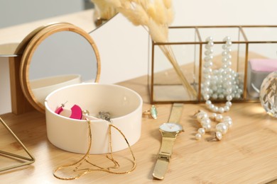 Photo of Jewelry box with many different accessories, wristwatch and decor on wooden table