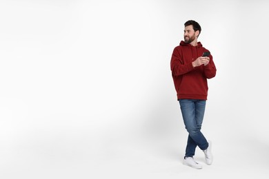 Happy man with smartphone on white background. Space for text