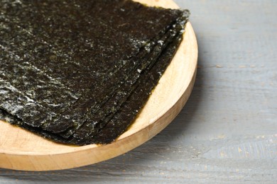 Dry nori sheets on grey wooden table, closeup