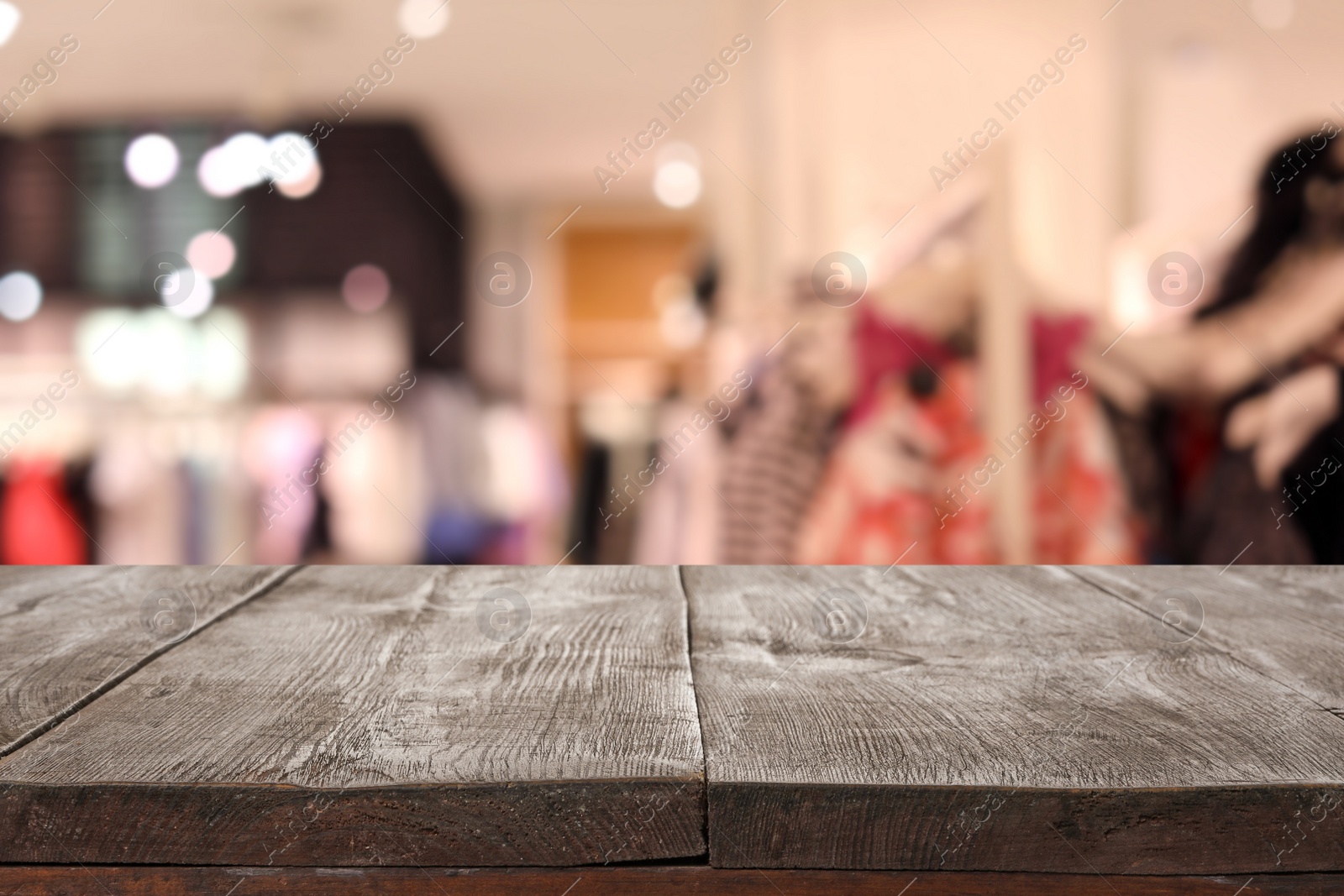 Image of Empty wooden table and blurred view of store with modern clothes