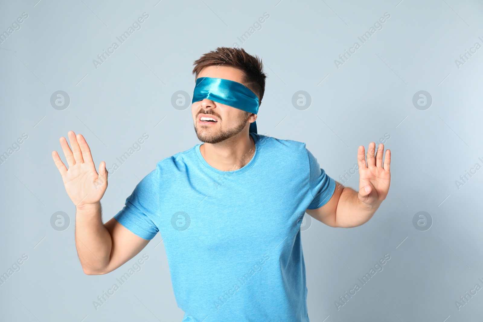 Photo of Young man with light blue blindfold on grey background