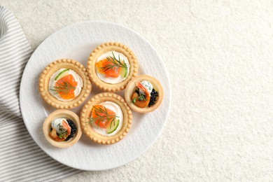 Delicious canapes with shrimps, salmon and caviar on beige textured table, top view. Space for text