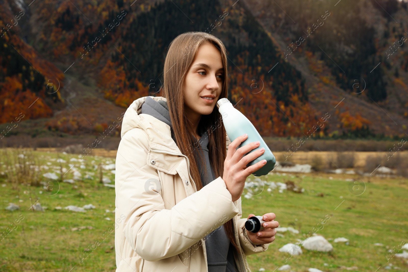 Photo of Woman drinking from thermo bottle in beautiful mountains