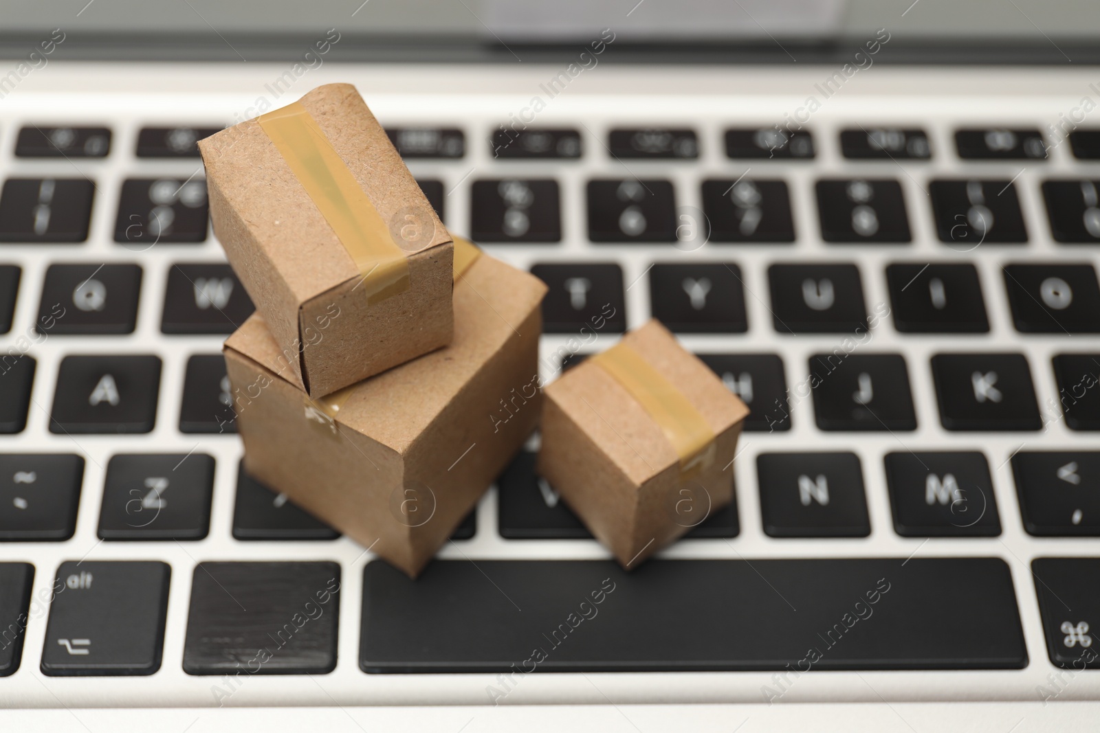 Photo of Internet shopping. Small cardboard boxes on laptop, closeup