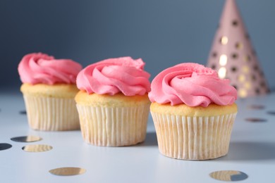 Photo of Delicious cupcakes with bright cream and confetti on light background, closeup