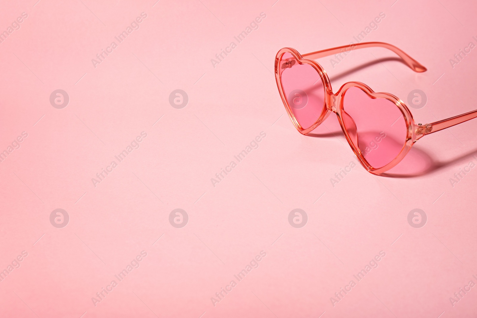 Photo of Stylish heart shaped glasses on color background. Space for text
