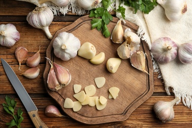 Photo of Flat lay composition with fresh sliced and whole garlic on wooden table. Organic product