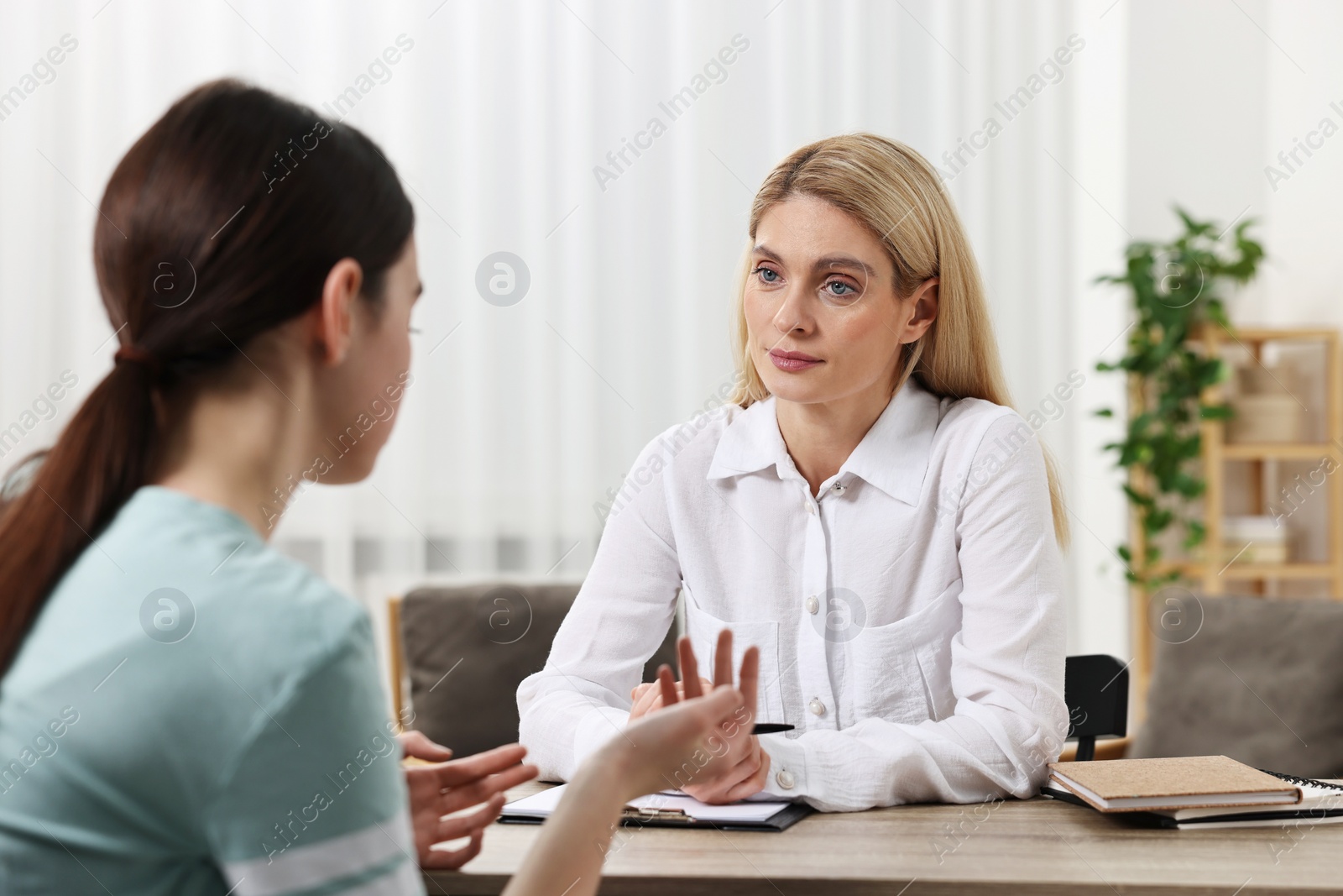 Photo of Psychologist working with teenage girl at table in office