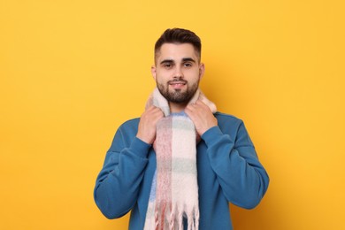 Photo of Smiling man in warm scarf on yellow background