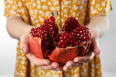 Photo of Woman holding fresh pomegranate on light background, closeup