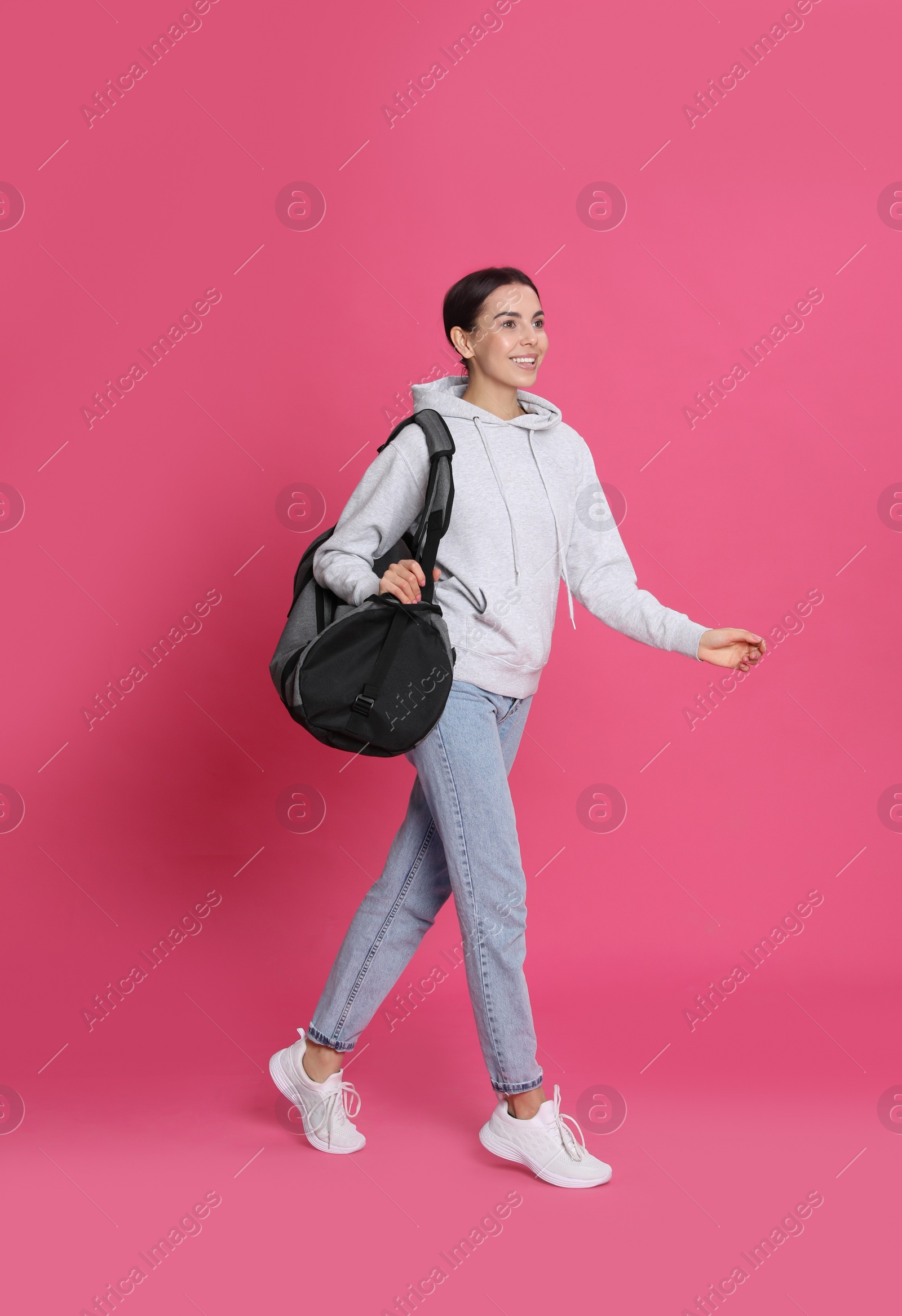 Photo of Beautiful woman with sports bag on pink background