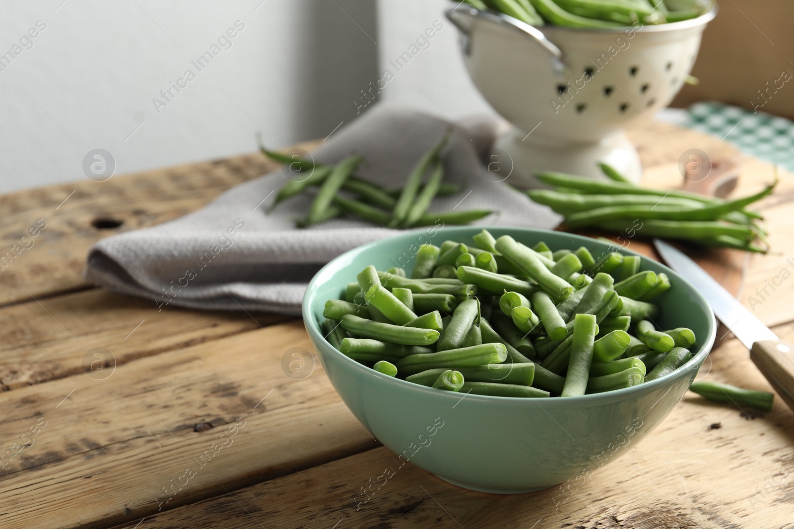 Photo of Fresh green beans in bowl on wooden table, space for text