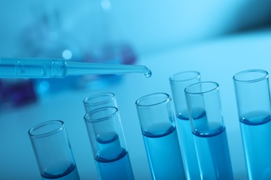 Photo of Dripping reagent into test tube with blue liquid, closeup. Laboratory analysis