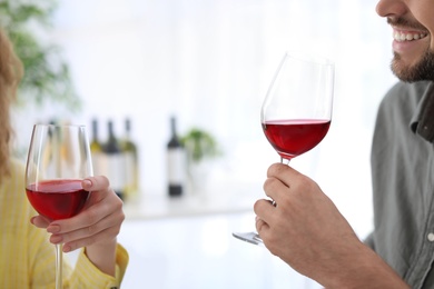 Young couple with glasses of delicious wine indoors