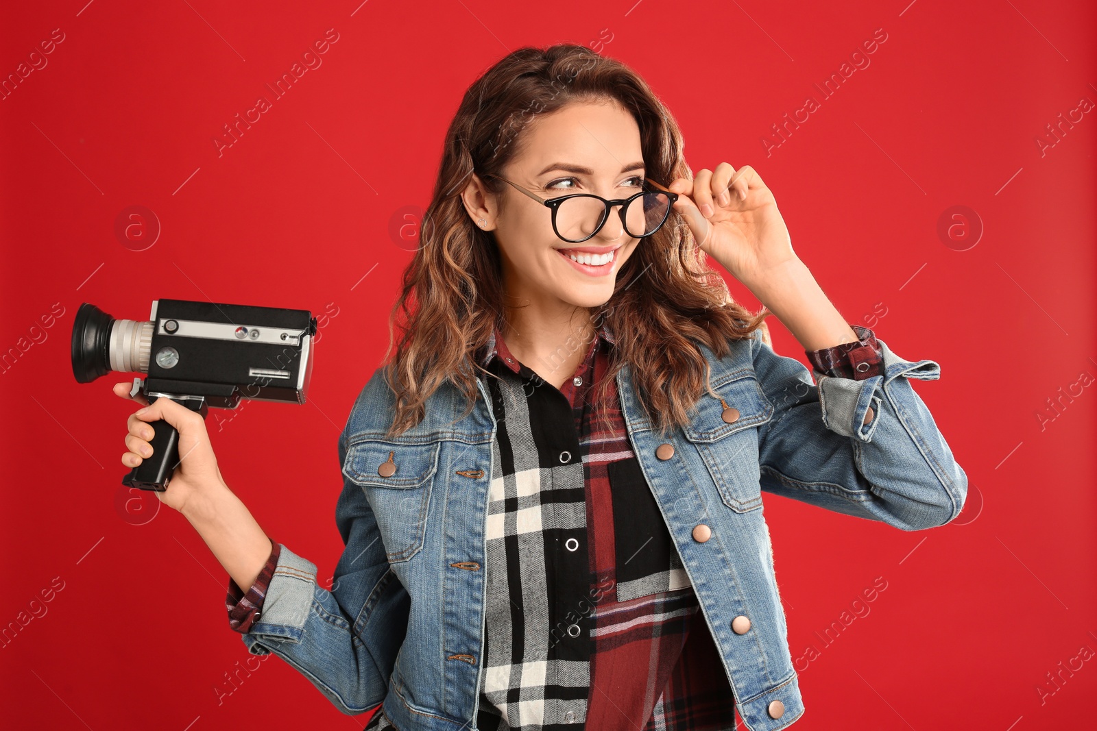 Photo of Beautiful young woman with vintage video camera on red background