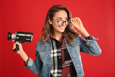 Photo of Beautiful young woman with vintage video camera on red background