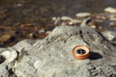 Photo of Compass on rock outdoors. Space for text