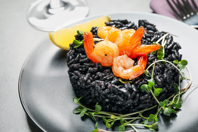 Delicious black risotto with shrimps on table, closeup