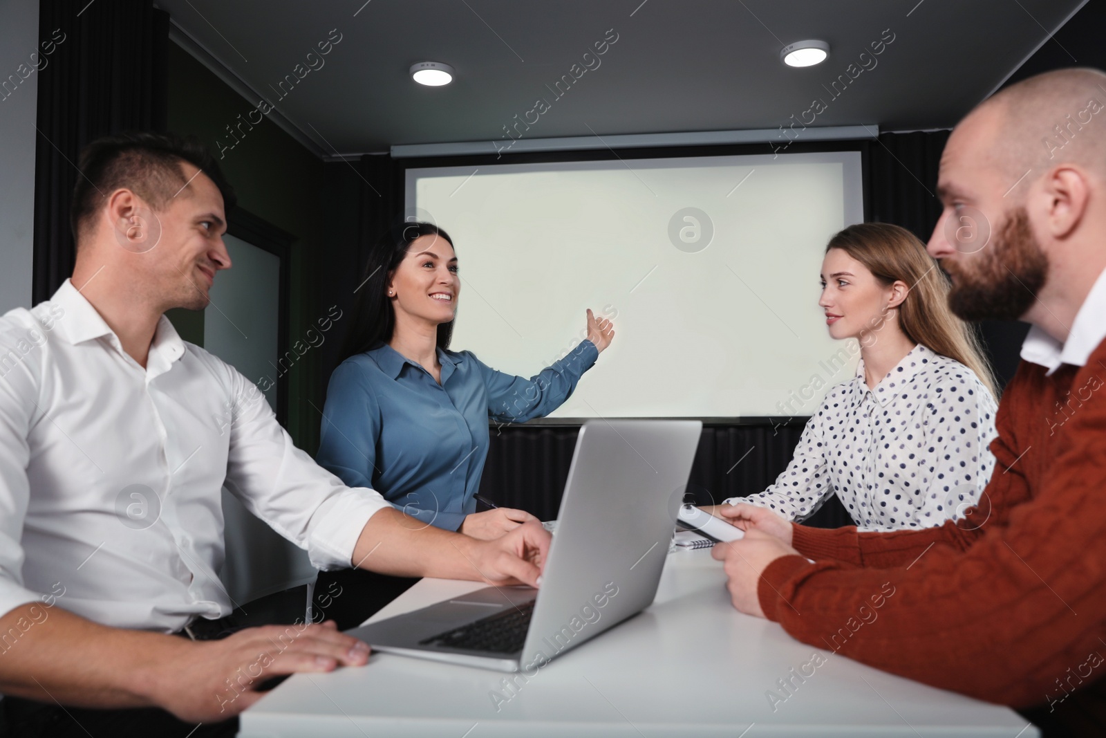 Photo of Business people having meeting in conference room with video projection screen