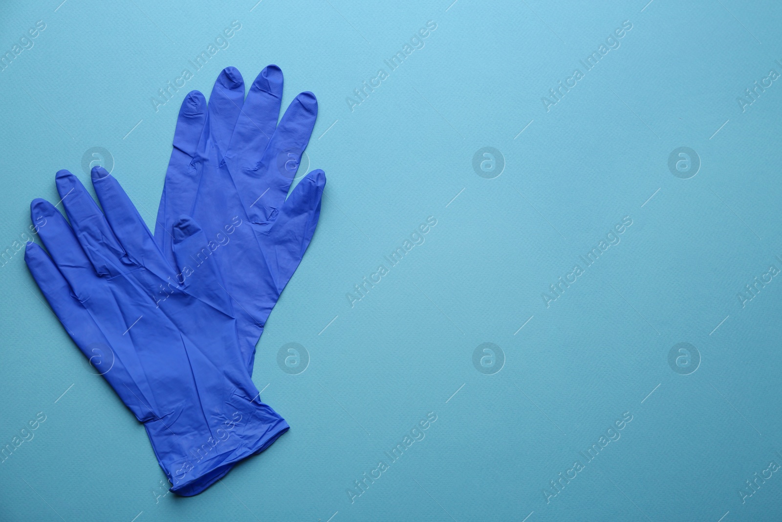 Photo of Pair of medical gloves on blue background, flat lay. Space for text