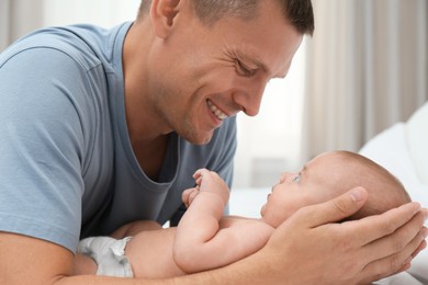 Happy father with his cute baby on bed at home