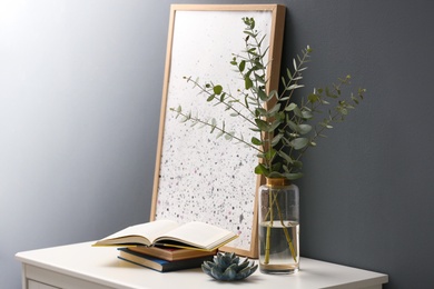 Beautiful eucalyptus branches on white table near black wall in modern room. Interior design