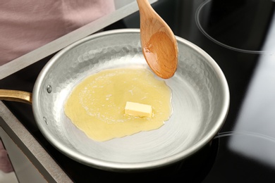 Stirring melted butter on frying pan in kitchen, closeup