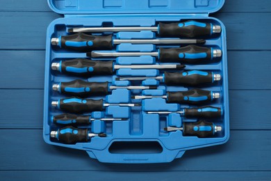 Photo of Set of screwdrivers in open toolbox on blue wooden table, top view