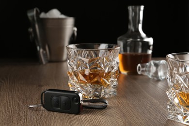Photo of Glass of alcohol and car key on wooden table. Drunk driving concept