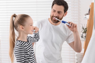 Photo of Father and his daughter brushing teeth together in bathroom