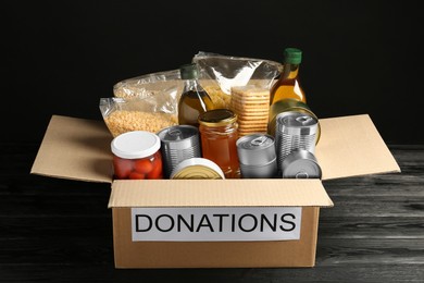 Photo of Donation box with food on black wooden table