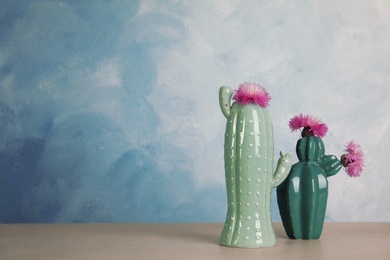 Photo of Trendy cactus shaped ceramic vases with flowers on table