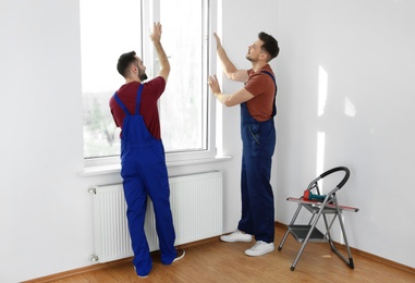 Photo of Construction workers installing plastic window in house