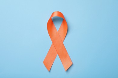 Photo of Orange ribbon on light blue background, top view. Multiple sclerosis awareness