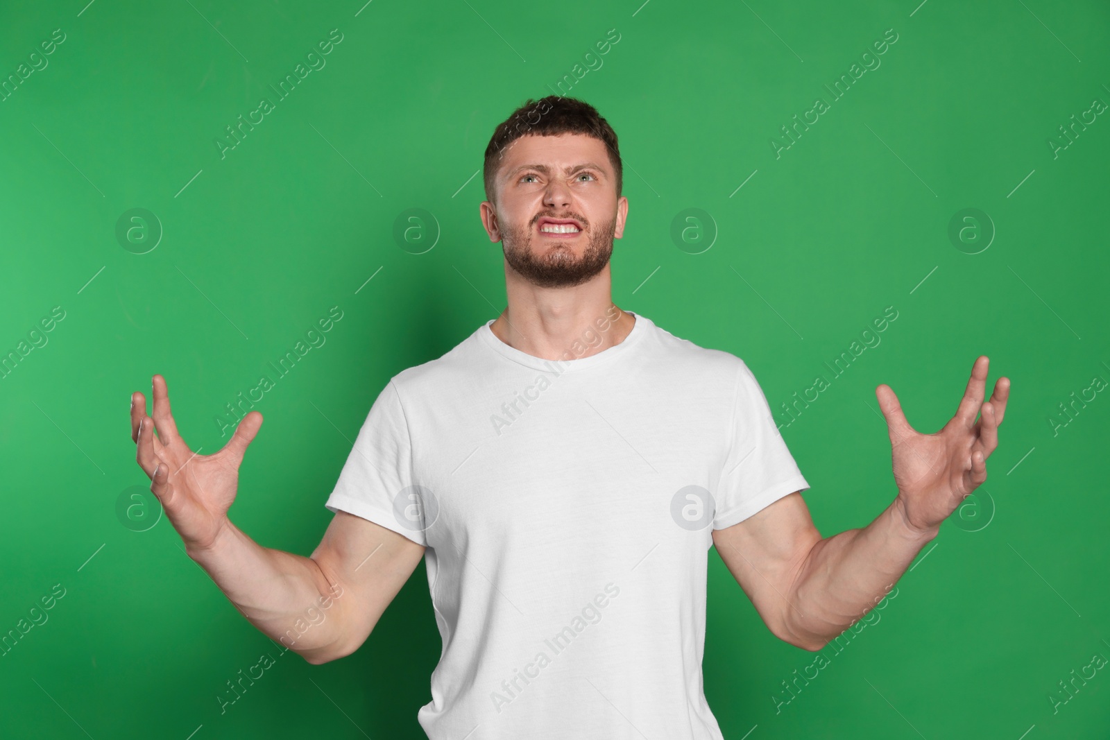 Photo of Emotional young man on green background. Aggression concept